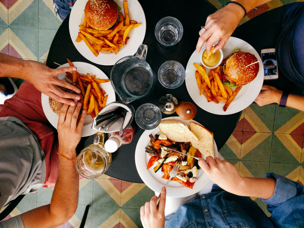 Four individuals with different meals at a restaurant table.