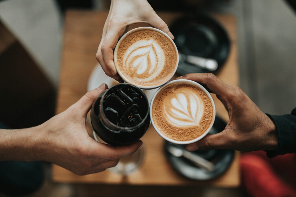 Three coffee drinks being held close together.